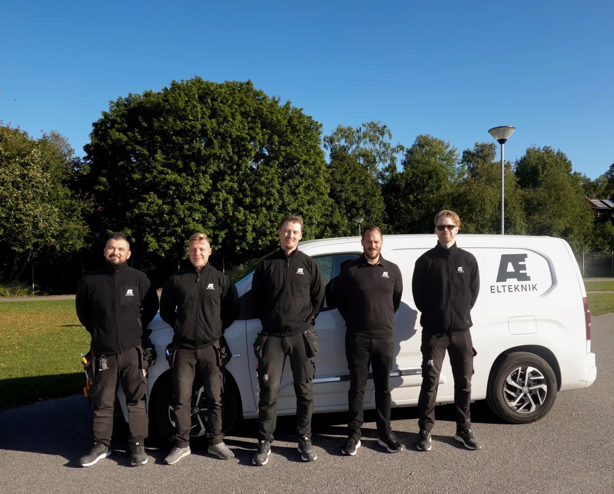 AE Eltekniks elektrikerteam framför företagets servicebil i Stockholm